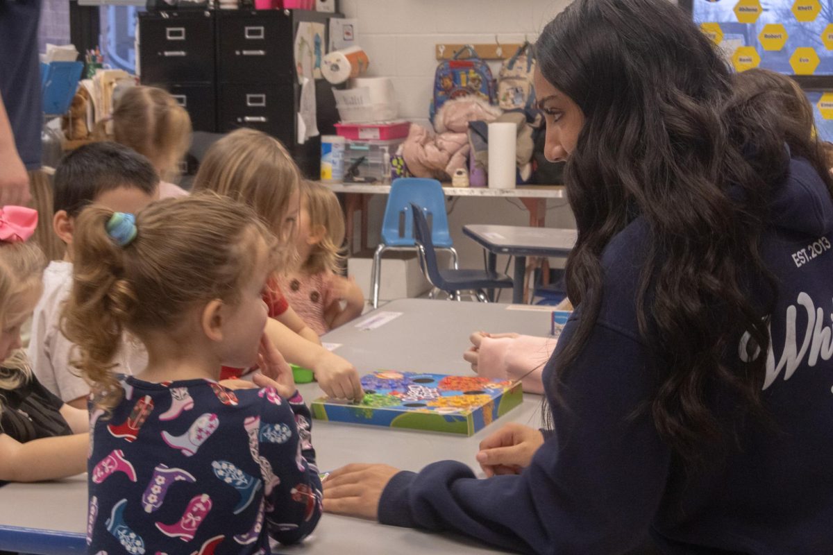 Ayah Elgazar talks to a student during a game of Hi Ho! Cherry-O on Feb. 18. Elgazar quietly reminds the little girl of the rules and how to properly play the game. 