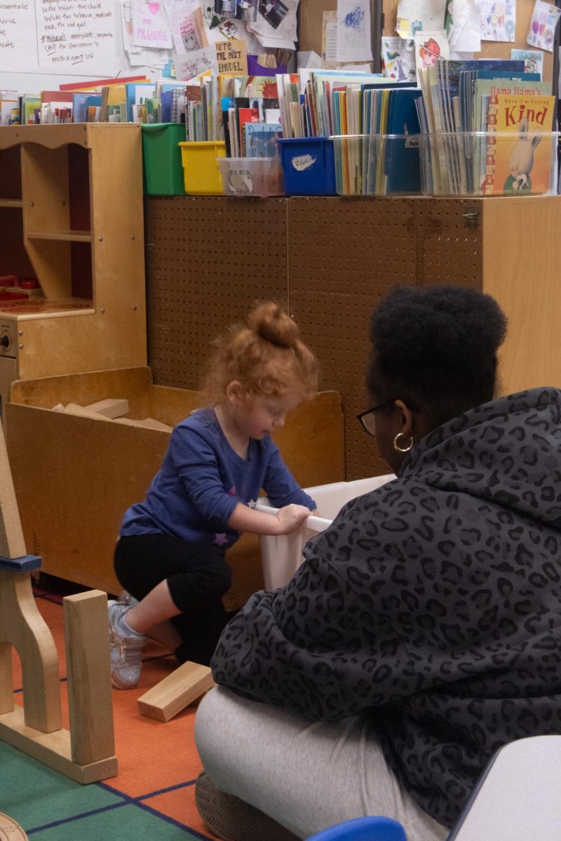 As blocks scatter at her feet the young girl drags out more. Senior Aela Kagarama  watches as she places more blocks on the ground surrounding one another on Feb. 18.
