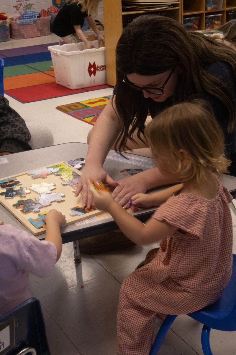 Taking a closer look Madi willis helps one of the little girls arrange the puzzle on the table on Feb 18. The little girl watches very intently as willis explains to her.