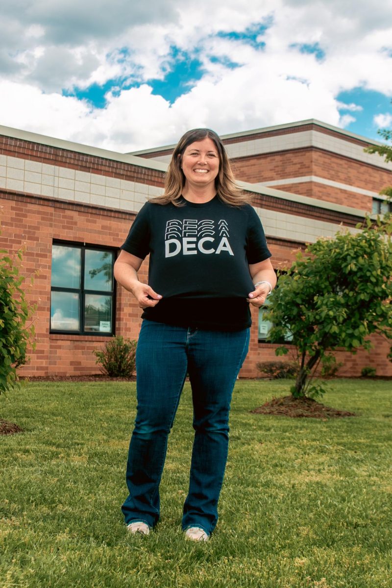 Lissa Range standing in front of Francis Howell Central showcasing her DECA shirt. Being an advisor for DECA, Range recently came back from internationals in Atlanta.