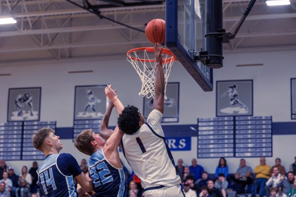 Senior Xavier Morrison attempts to make a basket while members of St. Dominic's team are prepared to take the ball. This was a district game that the boys varsity team won 54-50 to advance to the state quarterfinals.
