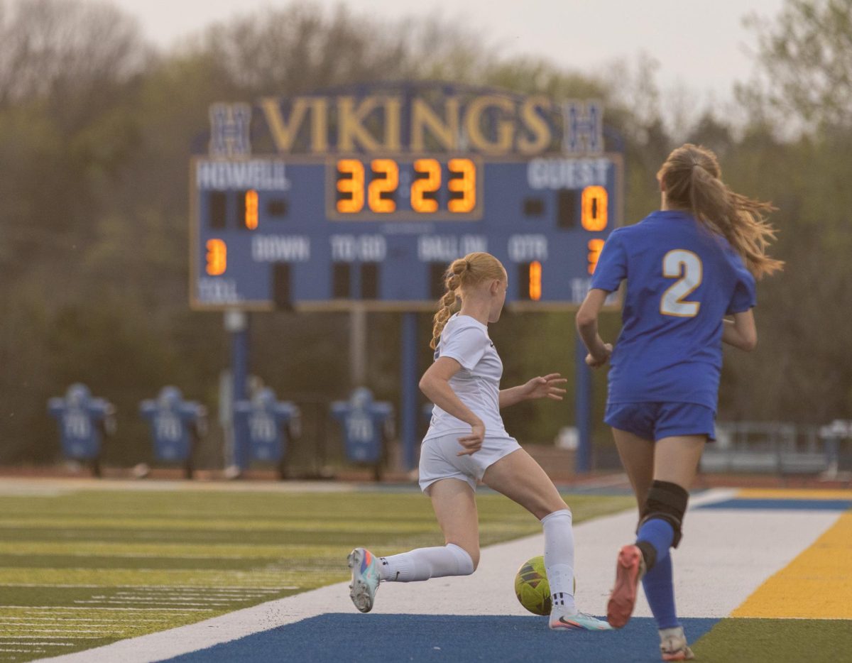  As freshman Chloe Bond runs down the field, the opponent follows after her. She protected and guarded the ball so she will be able to pass it to her teammates on April 9.
