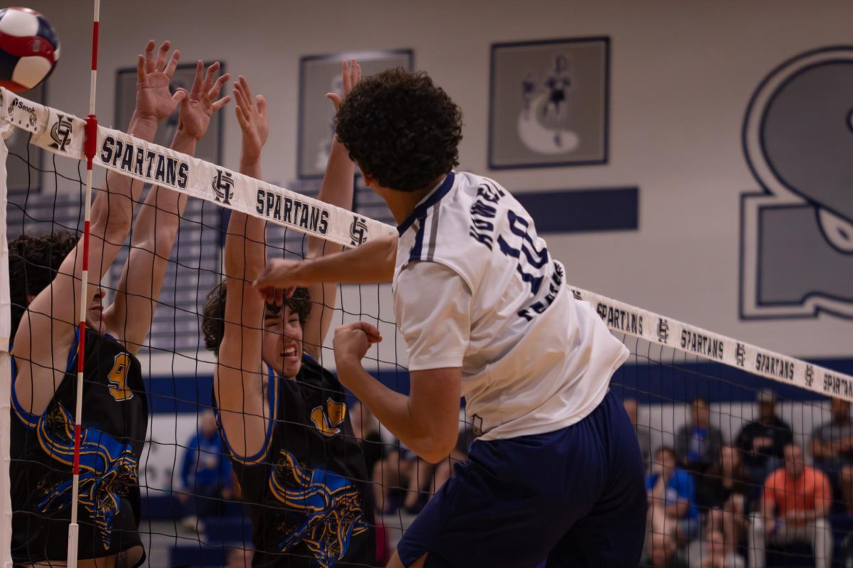 Leaping into the air, junior Nick Simpkins spikes the ball past the defenders for Howell on April. 21. The ball began to be volleyed back and forth until the Spartans gained a point.