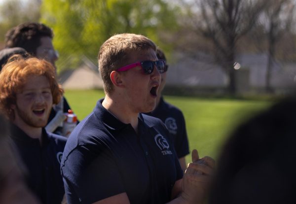 Wearing pink sunglasses, senior Dimitry Babey shouts as his teammate is called to the courts on April 6. Babey kept up his enthusiasm for each Spartan tennis player as their names were listed.