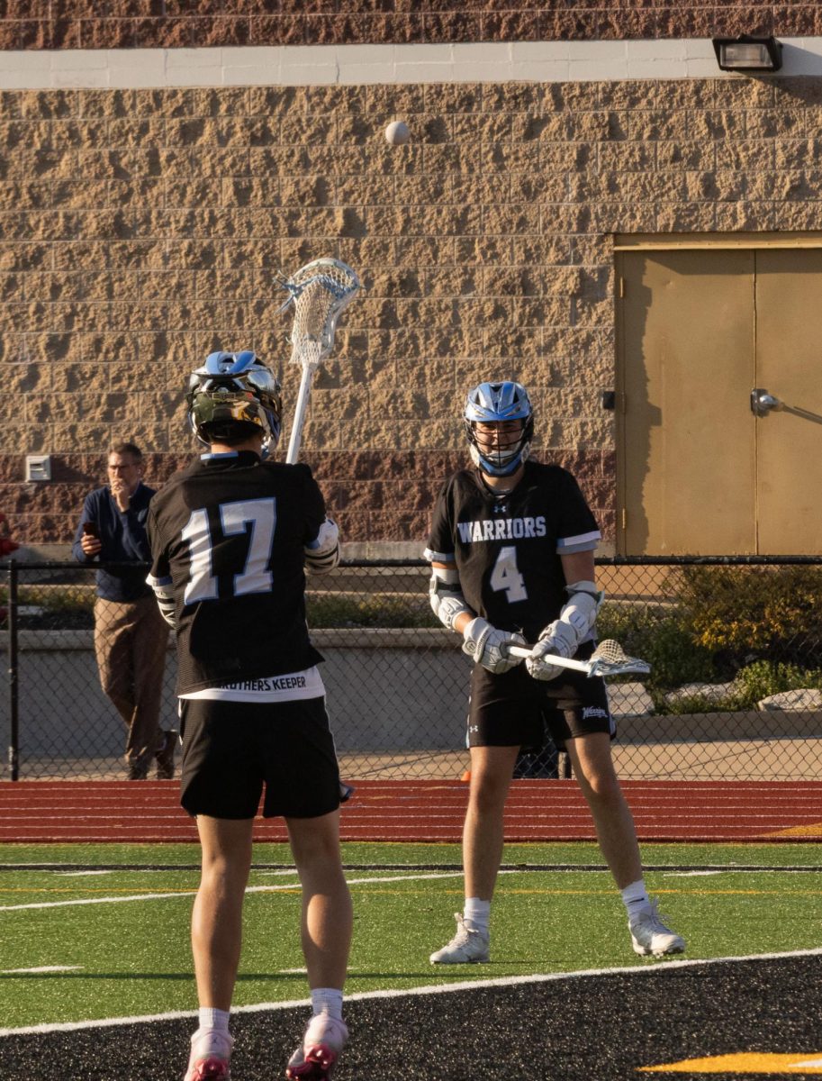 Passing the ball between each other behind the net at the game on April 7th, juniors Riley Findall and Jack Ney try to find a way to score. They had to use each other to get goals since lacrosse is a team sport. 