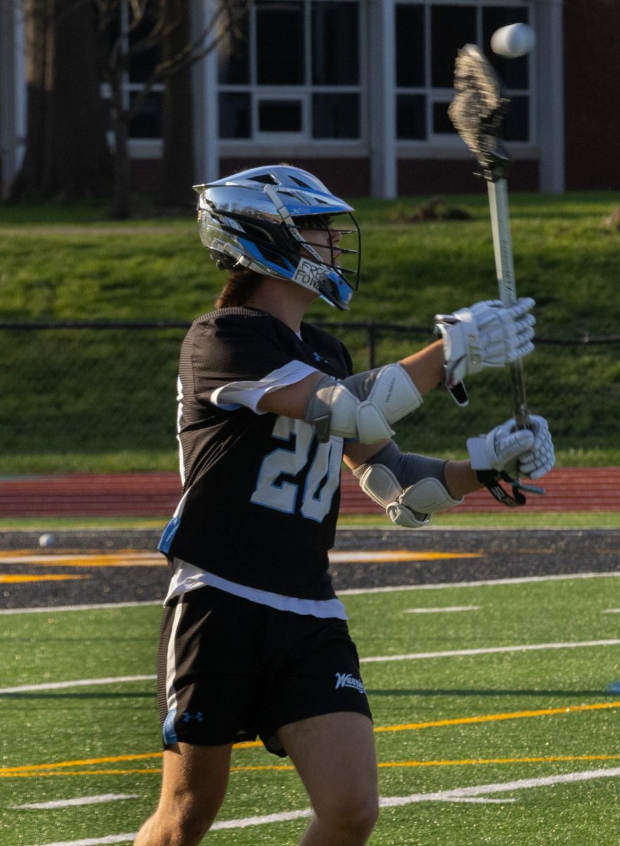 Passing the ball to his teammate, junior Aidan Wood throws the ball out of his stick at the game on April 7th. Wood had to make sure that there was no one around when he passed to his teammate so that the other team doesn't over turn the ball.