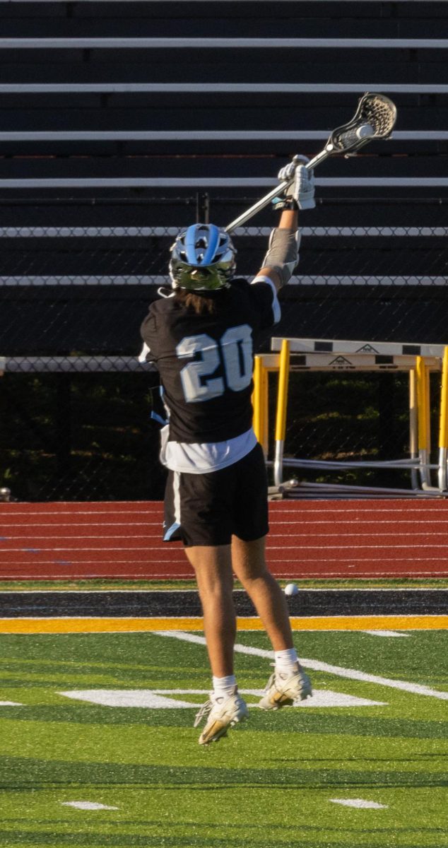 Reaching up to catch the ball at Vianney on April 7th, junior Aidan Wood leaps into the air for a badly passed ball. The team has worked on their passes through after school practices.