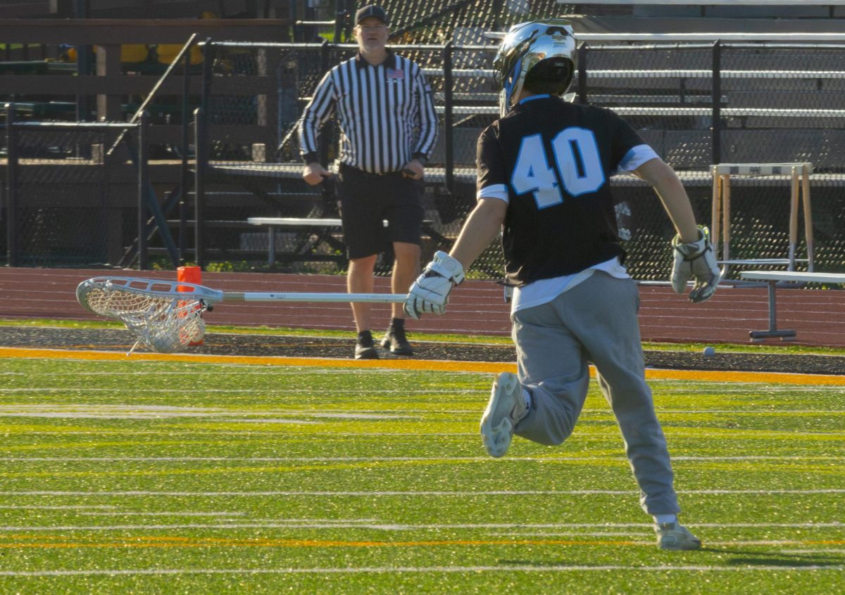 Runnning with the ball away from the net, goalie and senior Evan Dick makes sure the area is empty before clearing the ball at the game on April 7th. Dick has played all 4 years of high school and is the starting goalie on varsity.