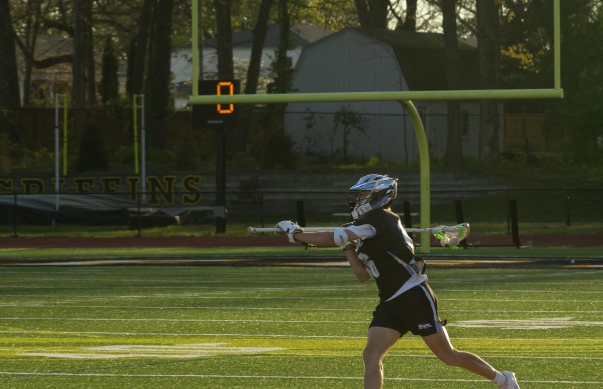 Senior Ryan Wessler pulls his stick back to launch the ball to his teammate across the field at the game on April 7th. The team practiced passing at practice to make sure they can pass the ball to each other well.