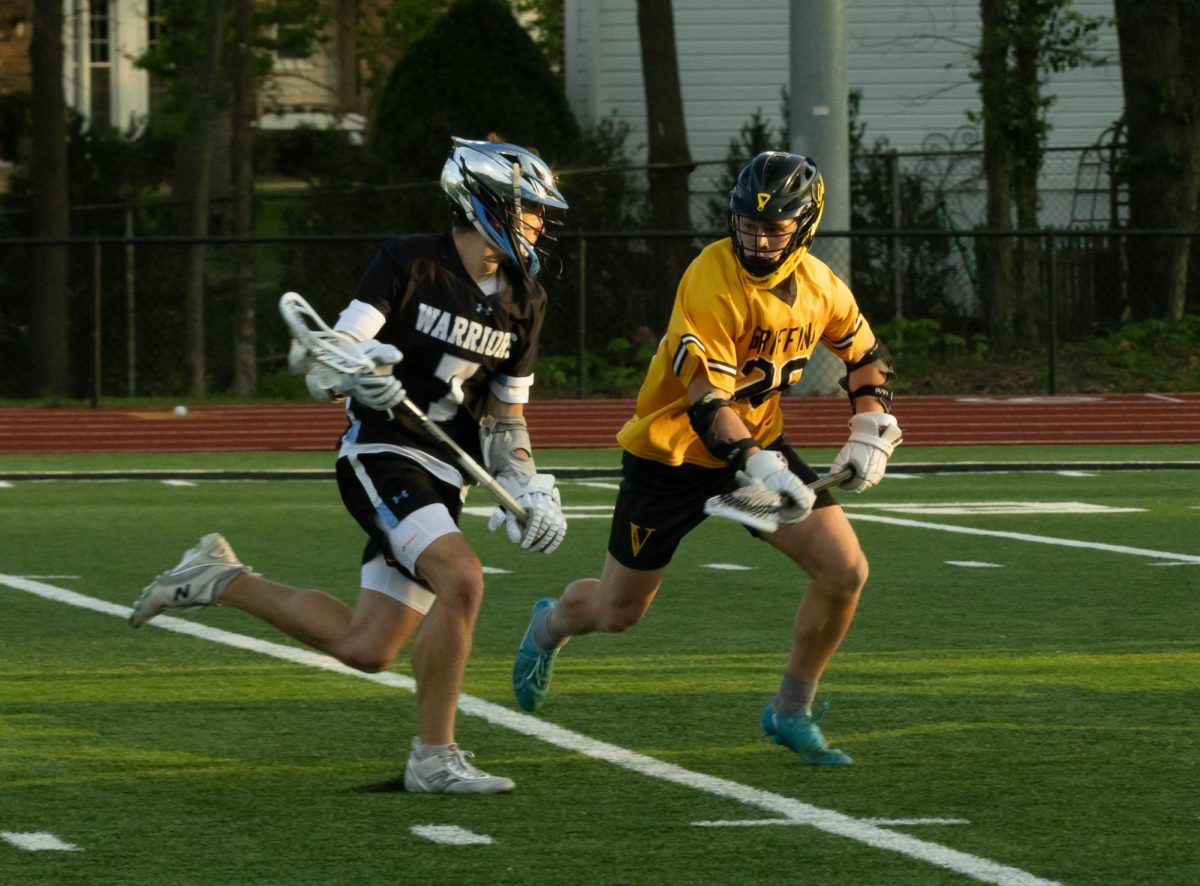 Junior Matt Babb holds his stick away from the opposing team’s player that is trying to get the ball from him at Vianney on April 7th. Babb had been running towards the goal to try and score for his team. 