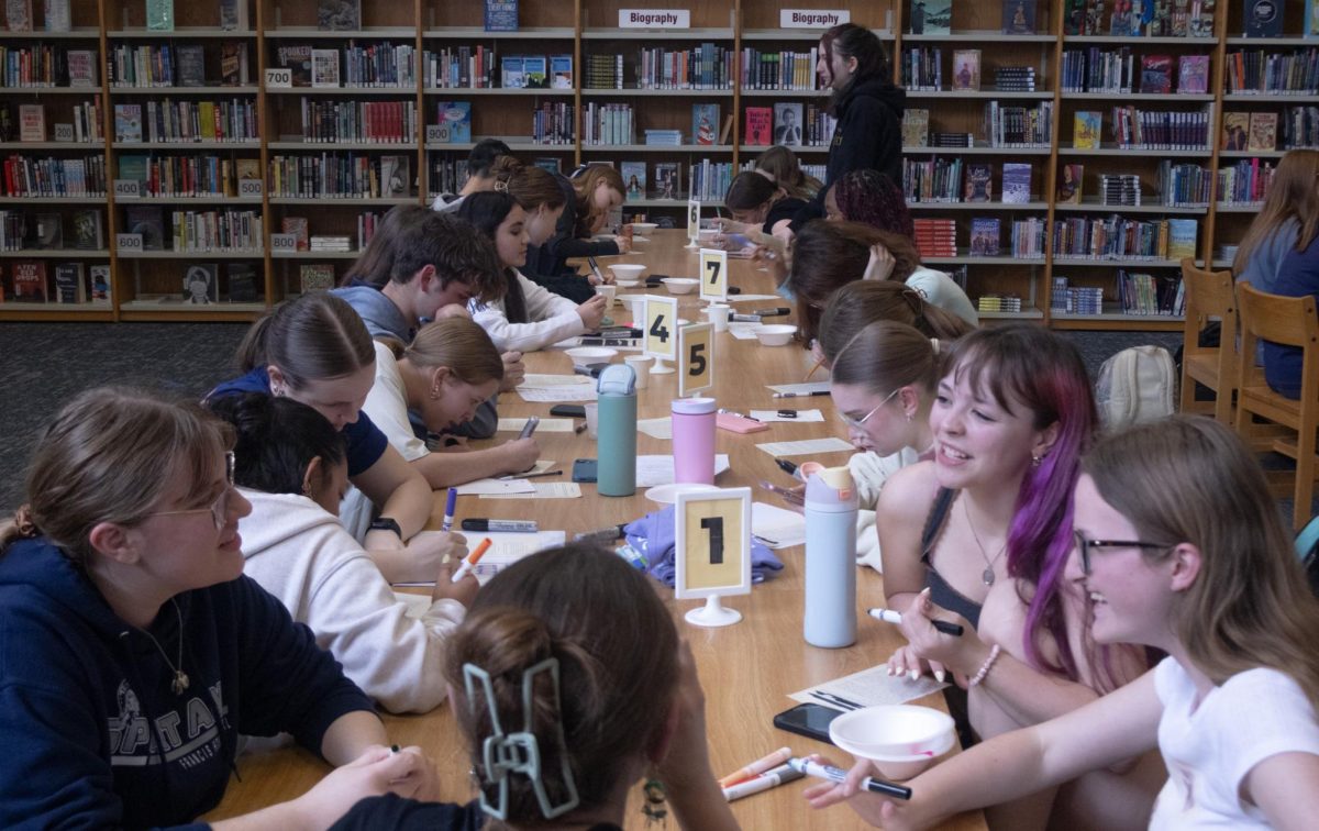 Some members of Epsilon Beta and their friends talk about the ideas they have for their blackout poems, while others diligently mark out words and draw pictures on their pages on April 15. As students finish, they store their works of art to take home as keepsakes for the last Epsilon Beta social of the year.