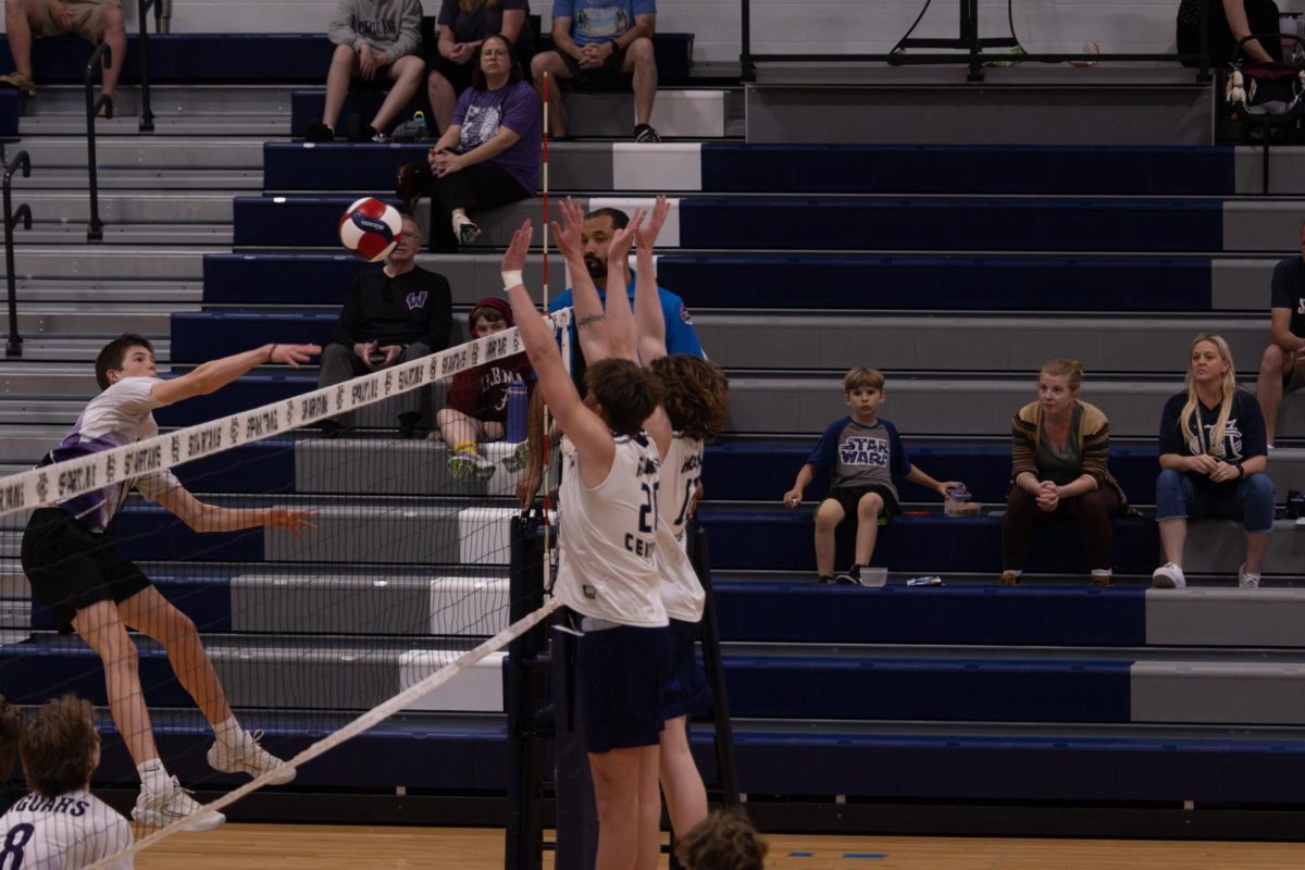 Jumping to block the attack from the opposing team, junior Kevin Wittig and sophomore Owen Barbeau hold their arms high to block as much as they can on April 23. If the opponent smashes the ball into the net, the team chants “How high is the net? Too high!”