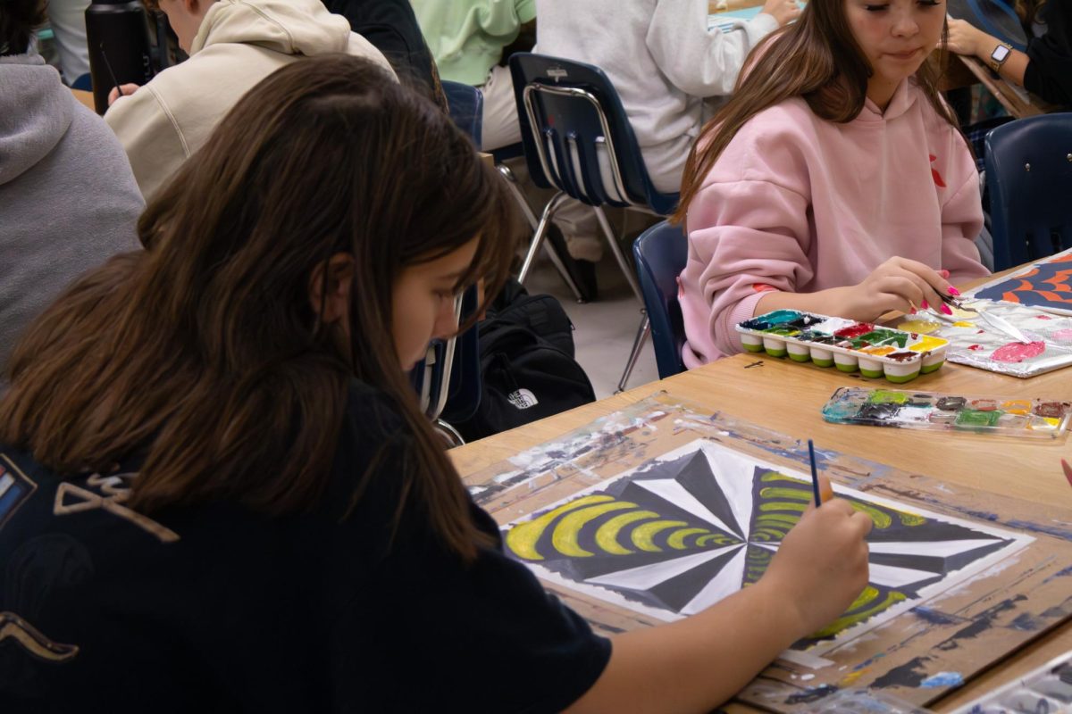 On Nov. 12, sophomore Gabby Krebs finishes the last parts of her painting. She focuses on the precise lines she places her brush on to make the illusion look like it's going into the paper.
