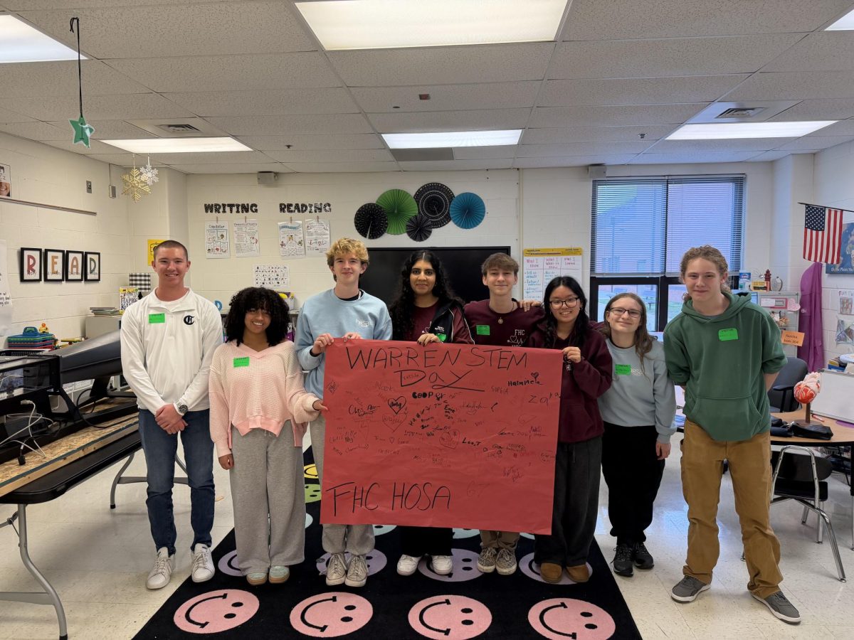 Members of HOSA, Matt Luskowski, and Jarret Reed proudly stand behind a STEM day poster. The poster is signed by all the students who volunteered for STEM day as well as the students of Warren Elementary.