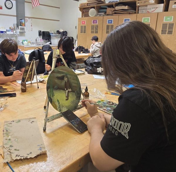 Senior Dayton Pagano lifts his hand, but pauses. Is that that the creepy un-hooded figure ready to have the final strokes of paint before turning into one of the masterpieces? 