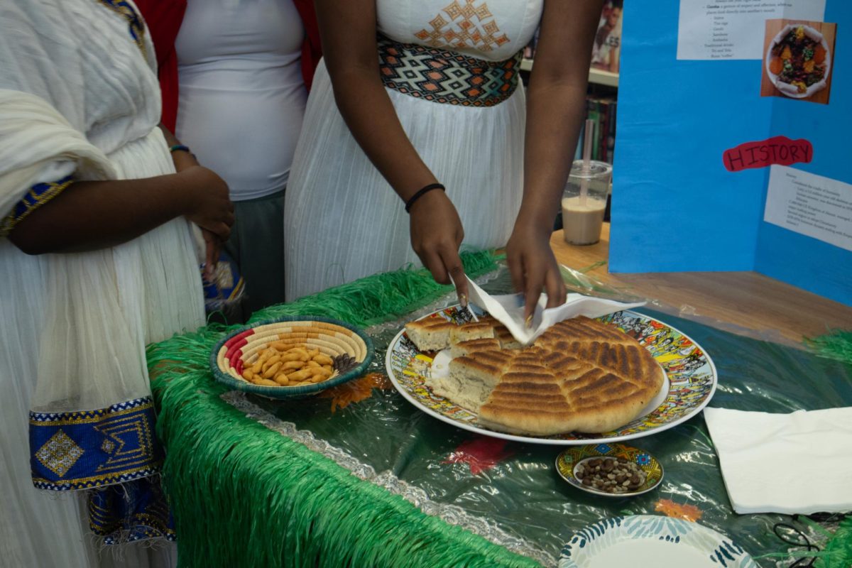 Nuwelin Dagne cuts a piece of bread as she explains the culture behind it. All the tables at the Culture Fair brought different traditional dishes to represent their cultures on April 29.