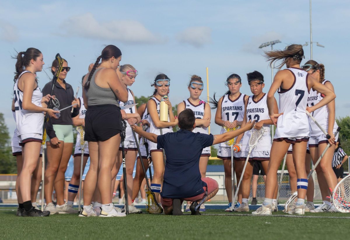 As Coach Angelina Dinello squats on the ground, she explains to the team what to do next on April 23. She uses her hands to show her team what plays they can use next to continue the game.