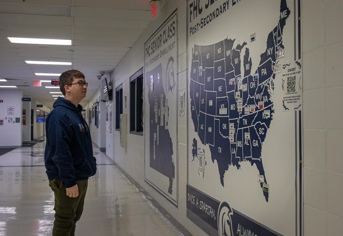 A senior student looks through the colleges that past students have chosen to go to, his glances scans the map, wondering as if where to apply. 