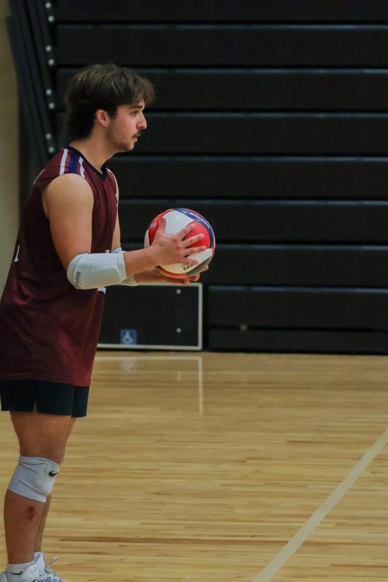 Taking a deep breath before he serves at the game on May 2, senior Braden Harton makes sure to concentrate on his serve. Not only is Harton a libero, but he also rotates to the back and serves the ball.