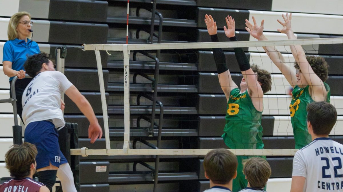 Swinging his arm down, senior Jason Campbell hit the ball over the net on to the other team's side at the game on May 2. Although there are blockers, Campbell aimed his hit around them.