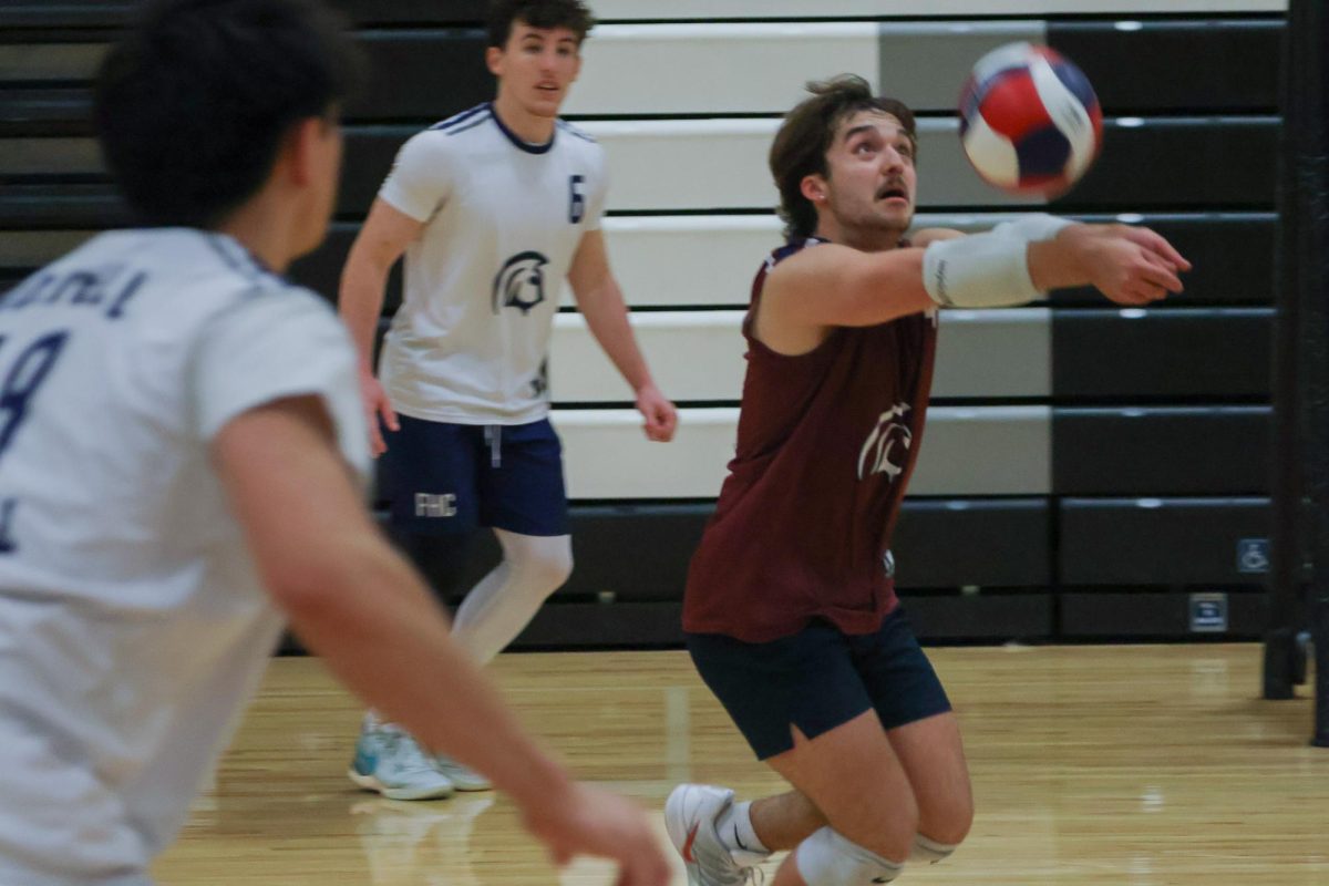 Rushing to get the ball up, senior Braden Harton gets low under the ball to make sure it stays in play for his teammates at the game on May 2. As a libero, Harton was the first one to start the rally.