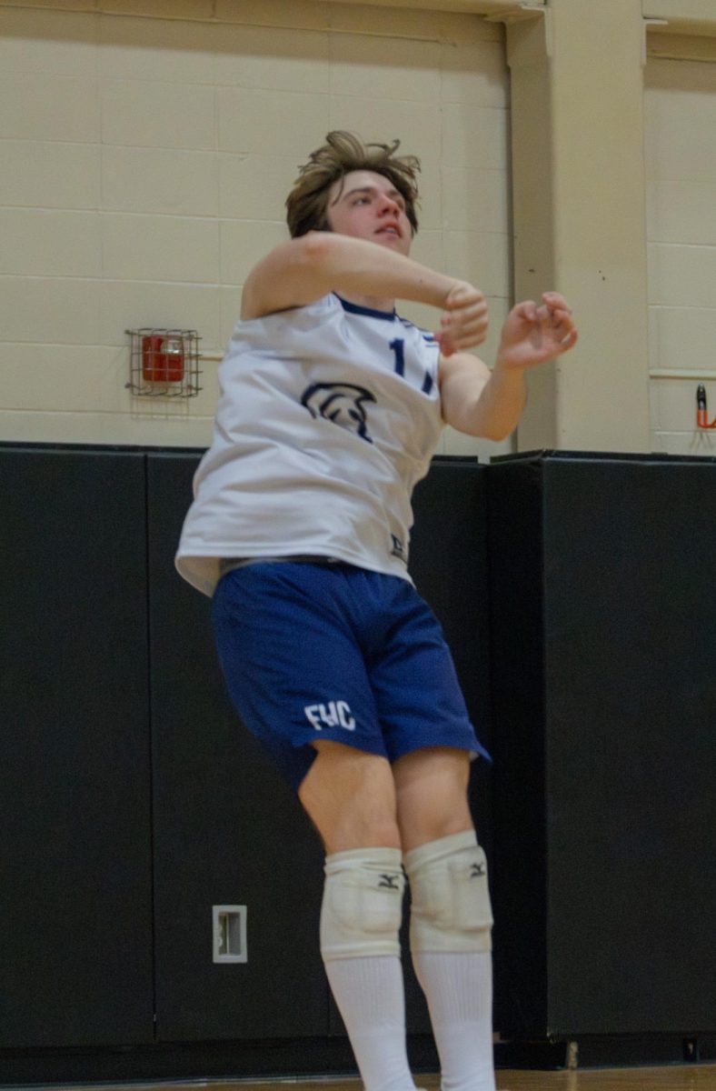 Coming down from hitting the ball, junior Joshua Hadden watches his ball go over the net at the game May 2. Hadden did a jump serve, meaning he launched the ball up then jumped to hit that ball.