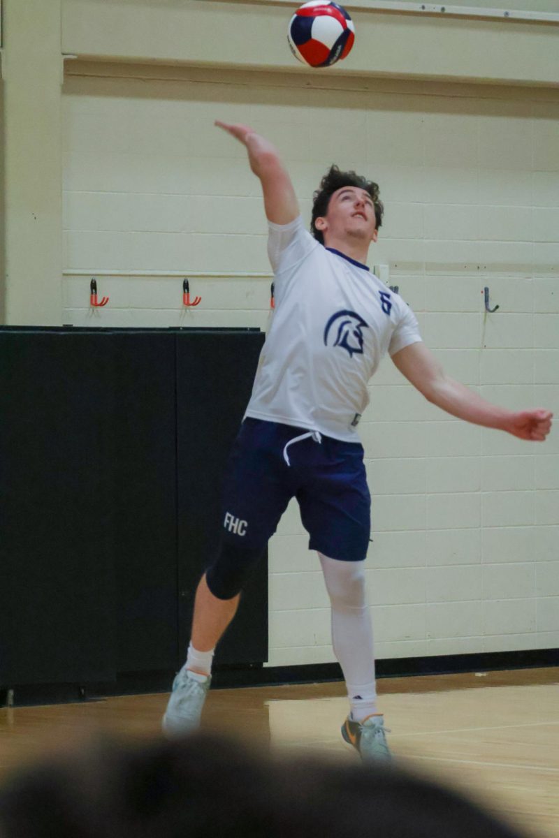 Senior Jason Campbell bends his hand back reaching toward the ball while he serves at the game on May 2. Campbell is a hard server and makes sure to aim toward players that he seems weak.