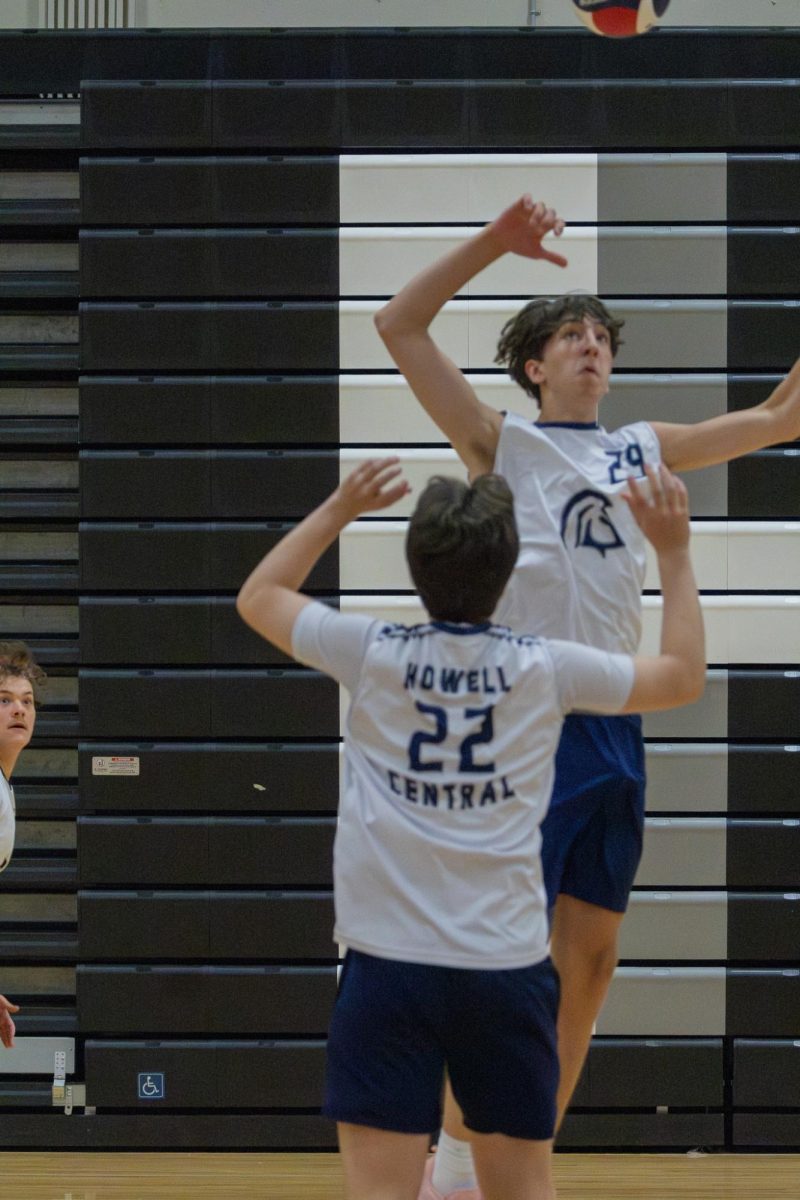 As the ball is set to him, junior Caleb Dolan reaches up waiting for the ball to come toward him so he can hit it at the game on May 2. The setter waited for the perfect time to set the ball so they could get a good hit.
