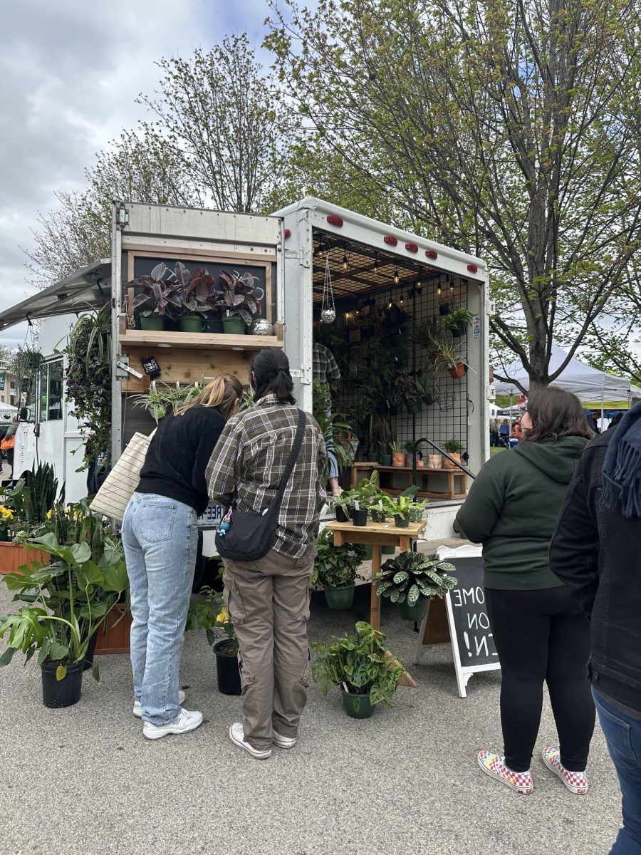 Two St. Louisans inspect a plant, contemplating which to buy from a portable garden market. 