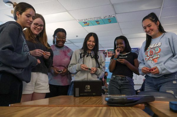 Members of Girls in Stem all laugh as they play a game on a console a member brought to the May 14 potluck. As the game continues it gets more hectic, filling the room with laughter. 
