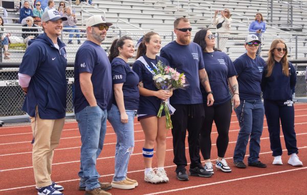 Senior Jaelyn Wooldridge poses with her family for a photo at senior night on April 29. After walking down the track under all the lacrosse sticks in the air, Wooldridge stood next to her family and coaches for a memorable picture.