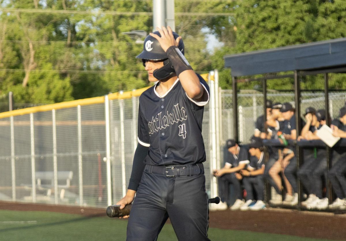 Junior Luke Hemby walks to bat with his hand adjusting his helmet at the game on April 24. Hemby bats with confidence and runs to first base following the pitch. 